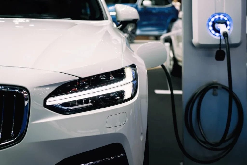Witte elektrische wagen aan laadpaal — ELF-straling van EV en laadpaal getransformeerd door Penta Power Car Vitaliser