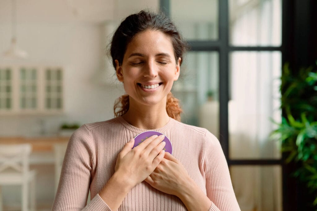 Vrouw houdt Penta Power Quantum Booster met gesloten ogen op haar hart — bewustzijnsondersteuning en EMF-bescherming in één