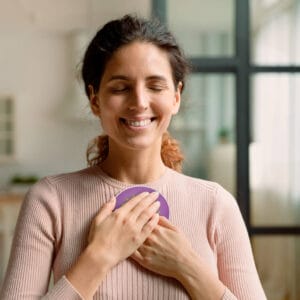Vrouw houdt Penta Power Quantum Booster met gesloten ogen op haar hart — bewustzijnsondersteuning en EMF-bescherming in één